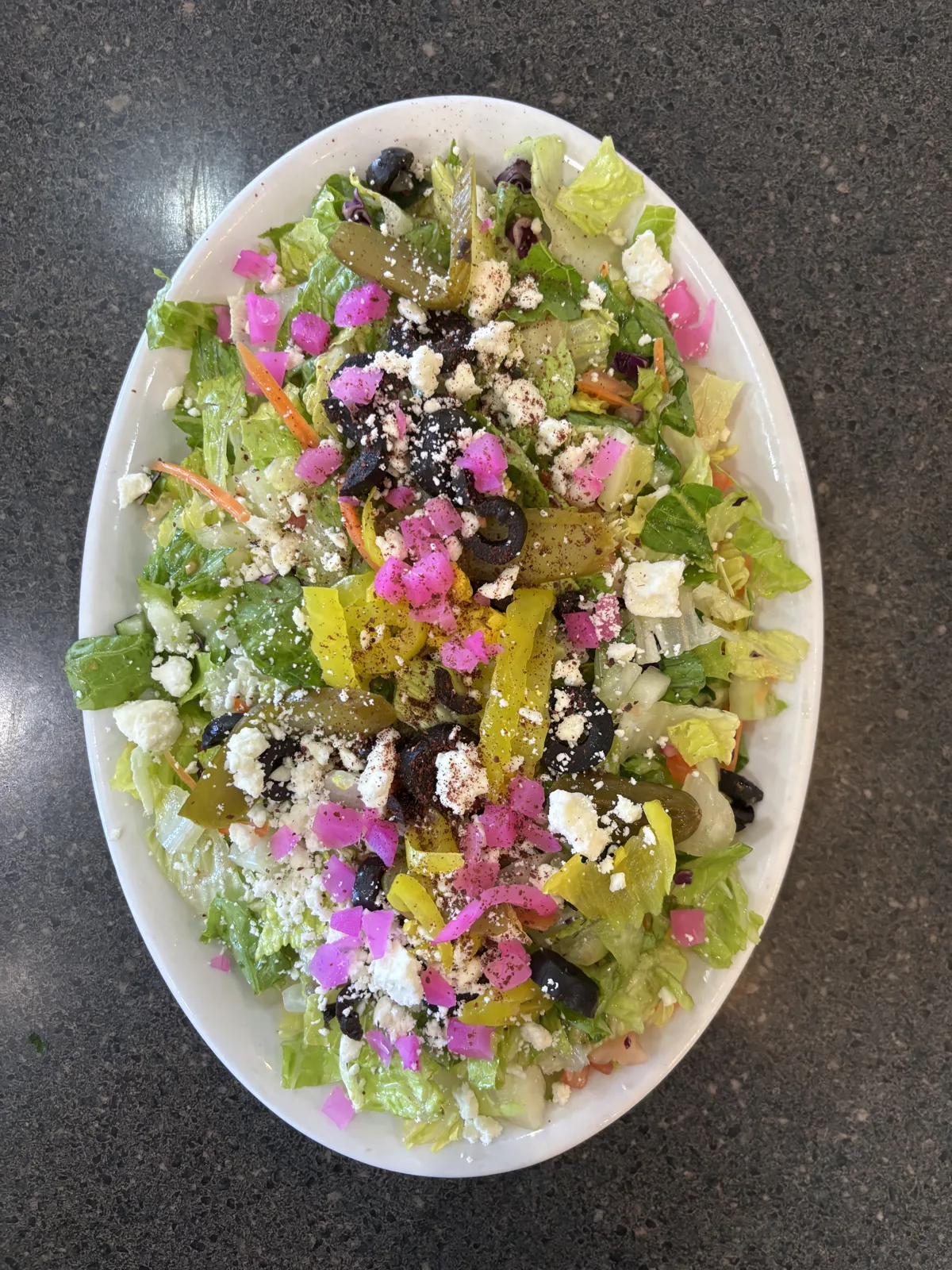 bowl of healthy fresh greek salad on white kitchen table