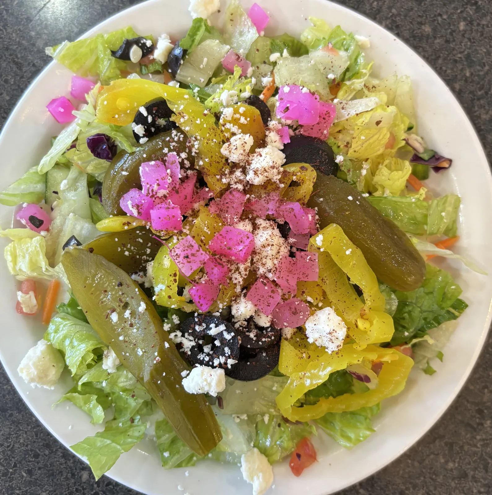 bowl of healthy fresh greek salad on white kitchen table